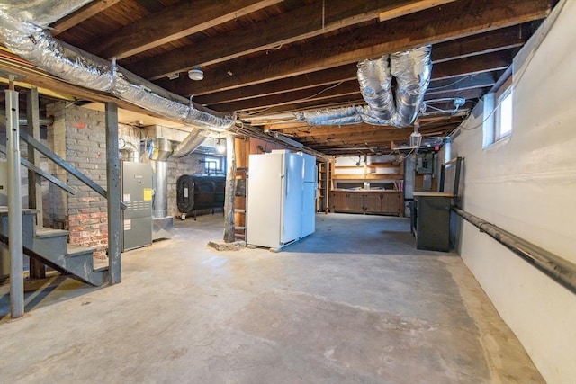 basement featuring freestanding refrigerator, heating unit, heating fuel, and stairs