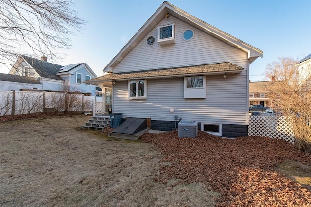 back of house with central AC unit and fence