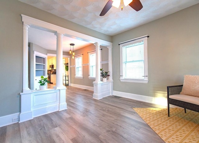 interior space with ornate columns, baseboards, and wood finished floors