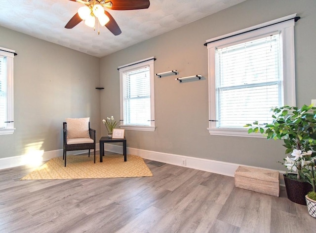 sitting room with wood finished floors, a ceiling fan, and baseboards