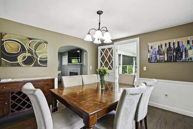 1112 Highland St, Holliston, MA 01746 - dining room featuring a fireplace, wood finished floors, arched walkways, a chandelier, and baseboards