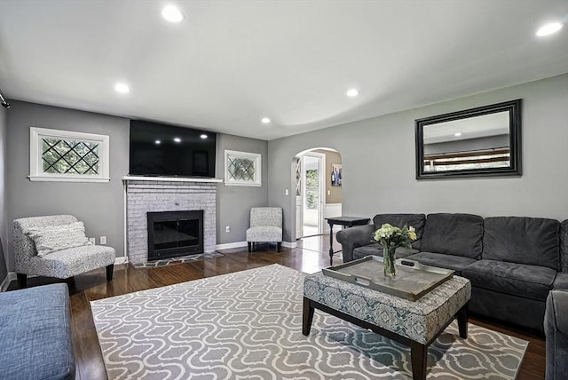 1112 Highland St, Holliston, MA 01746 - living room featuring arched walkways, recessed lighting, wood finished floors, a brick fireplace, and baseboards