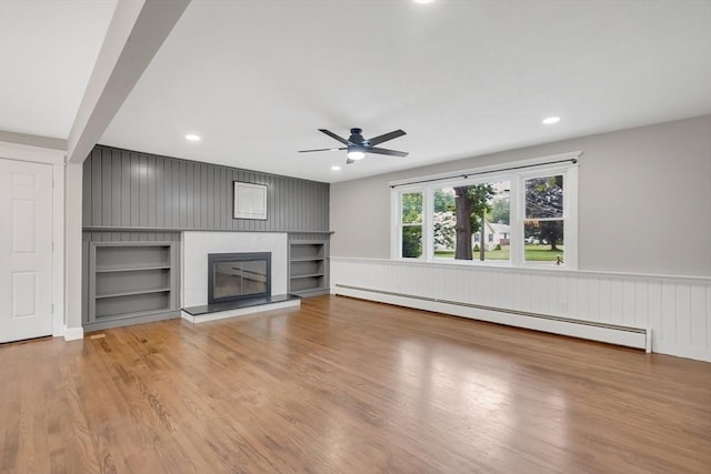 93 Pittroff Ave, South Hadley, MA 01075 - unfurnished living room with a baseboard radiator, ceiling fan, built in features, a glass covered fireplace, and wood finished floors