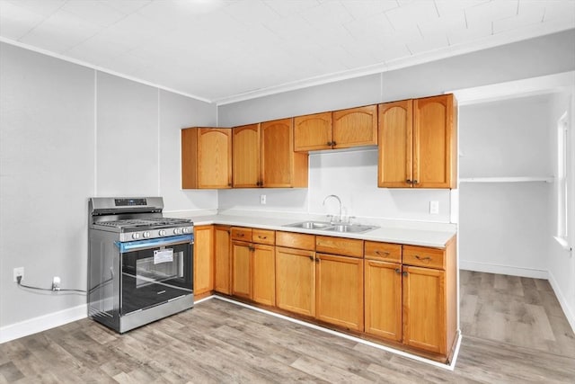 kitchen featuring light countertops, light wood finished floors, gas stove, and a sink