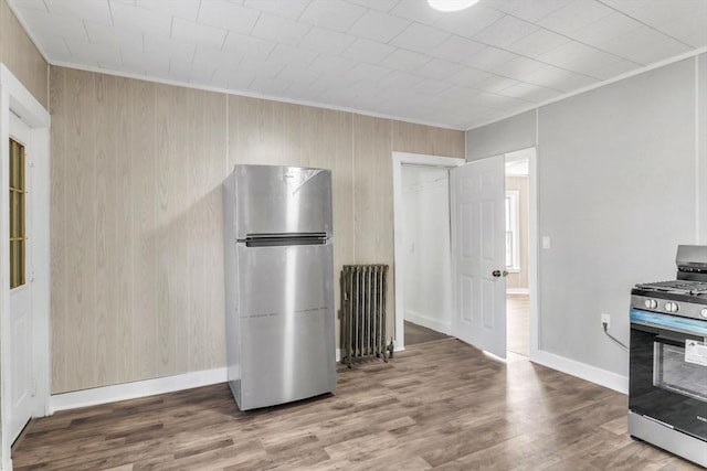 interior space featuring stainless steel appliances, crown molding, radiator heating unit, and wood finished floors