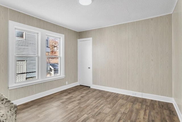 unfurnished room featuring ornamental molding, wood finished floors, and baseboards