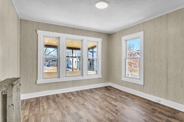 unfurnished room with crown molding, radiator heating unit, and wood finished floors