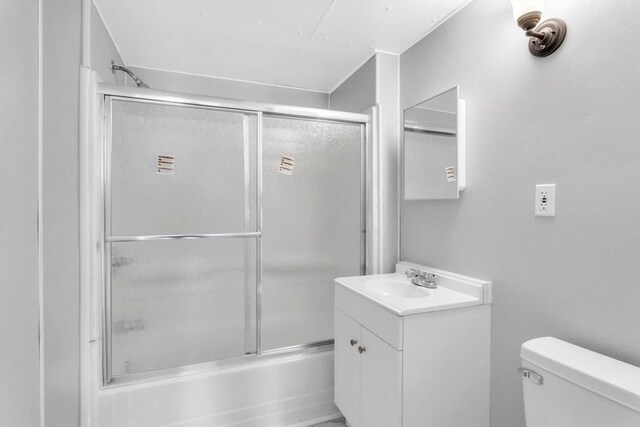 full bathroom with enclosed tub / shower combo, vanity, and toilet