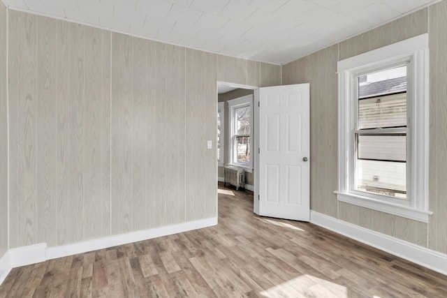 spare room featuring baseboards, radiator heating unit, and wood finished floors