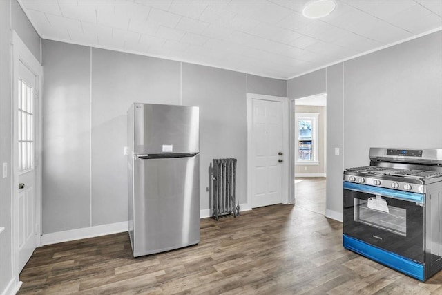 kitchen featuring baseboards, crown molding, appliances with stainless steel finishes, and wood finished floors