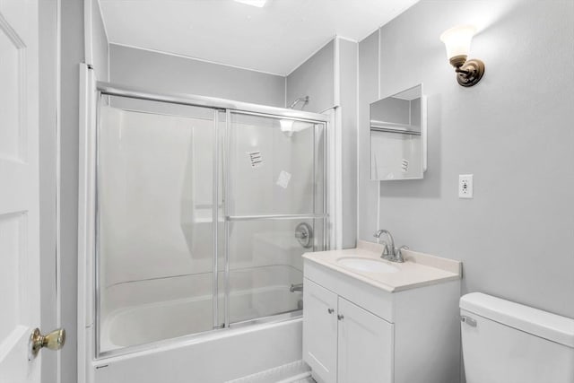 bathroom with bath / shower combo with glass door, vanity, and toilet