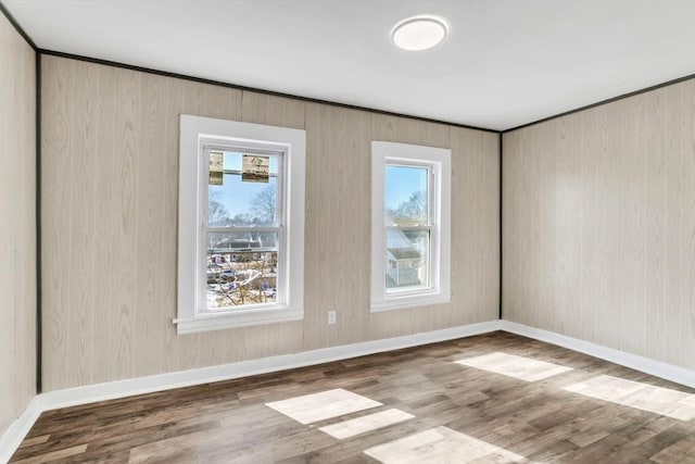 spare room with baseboards and wood finished floors