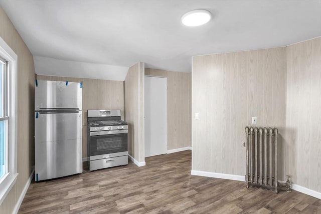 kitchen with stainless steel appliances, baseboards, radiator heating unit, and wood finished floors