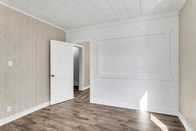 empty room featuring ornamental molding, wood finished floors, and baseboards