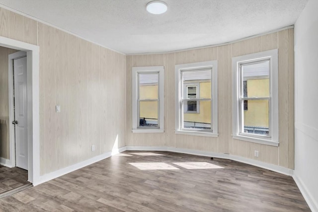 unfurnished room featuring a textured ceiling, baseboards, and wood finished floors