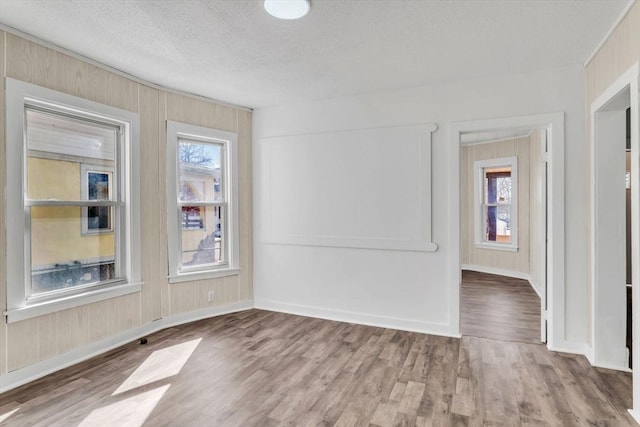 unfurnished room with a textured ceiling, plenty of natural light, and wood finished floors