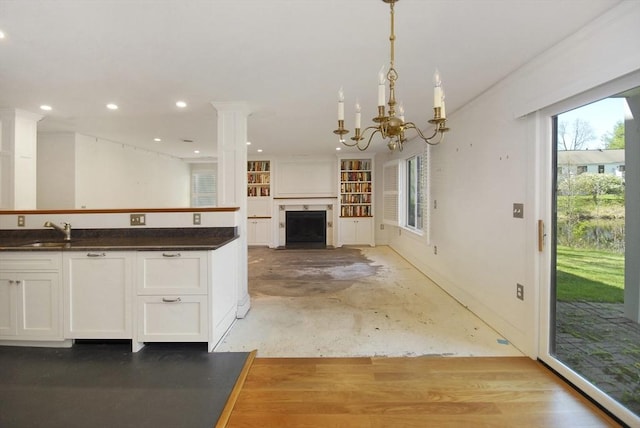 kitchen featuring white cabinets, dark countertops, a sink, open floor plan, and a fireplace with flush hearth