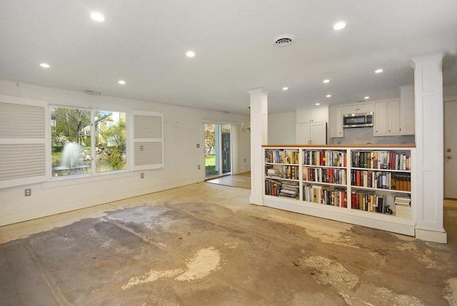 empty room with visible vents, decorative columns, unfinished concrete floors, baseboards, and recessed lighting