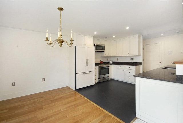 kitchen with stainless steel appliances, baseboards, a notable chandelier, and white cabinetry