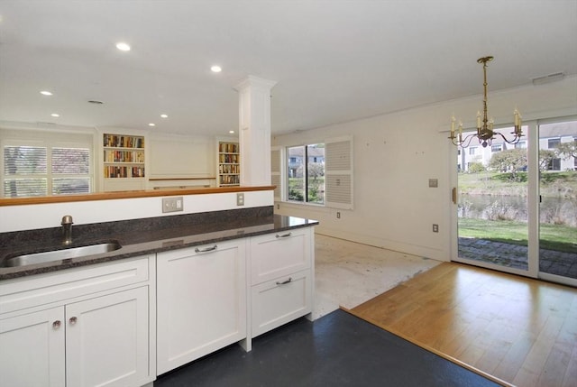 kitchen with white cabinetry, an inviting chandelier, plenty of natural light, and a sink