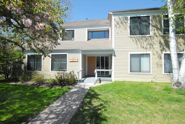 view of front of property with a shingled roof and a front yard