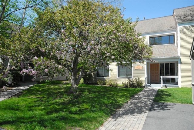 view of front of home with roof with shingles and a front yard