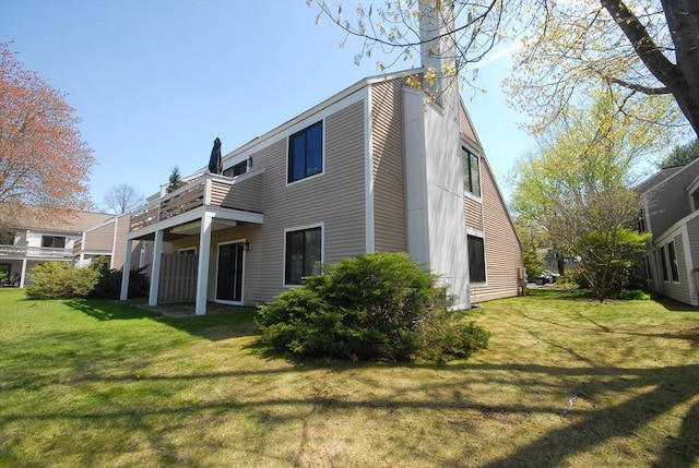 rear view of property with a chimney, a yard, and a balcony