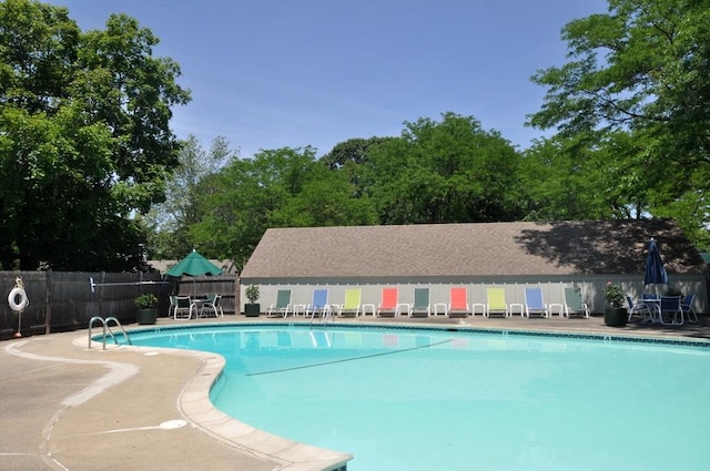 community pool with a patio and fence