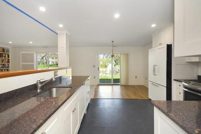 kitchen with white fridge, white cabinets, stainless steel range with gas stovetop, and a sink