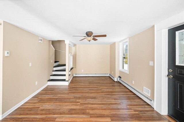 interior space featuring a baseboard radiator, a baseboard heating unit, a ceiling fan, wood finished floors, and stairs