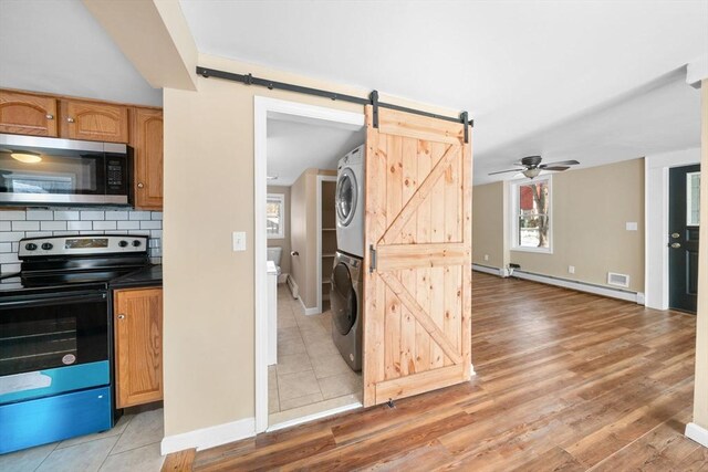 kitchen featuring stainless steel appliances, a barn door, stacked washer and dryer, and a baseboard radiator