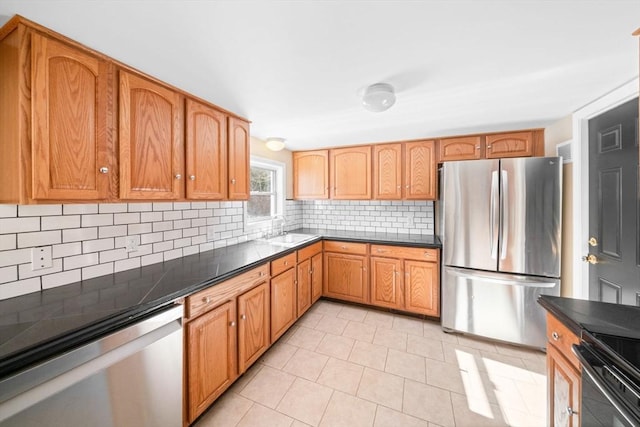 kitchen with dark countertops, a sink, stainless steel appliances, and decorative backsplash