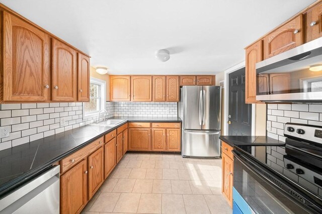 kitchen featuring appliances with stainless steel finishes, dark countertops, a sink, and tasteful backsplash