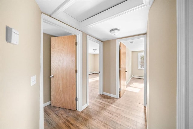 corridor featuring baseboard heating, light wood-style flooring, and baseboards