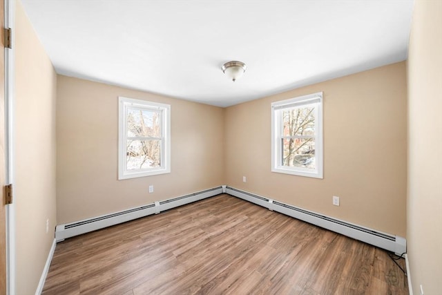 empty room featuring a baseboard heating unit and light wood finished floors