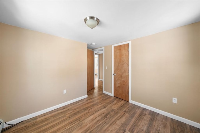unfurnished bedroom with a closet, wood finished floors, and baseboards