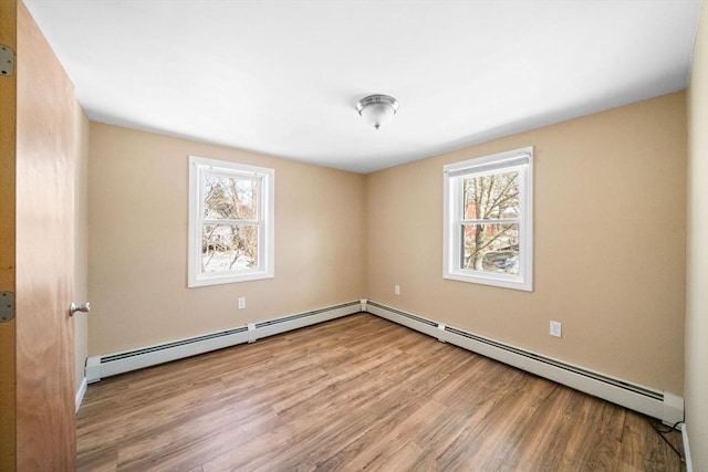 empty room with plenty of natural light, a baseboard radiator, and light wood-style floors