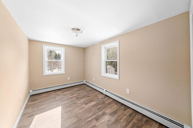 spare room with a baseboard heating unit, light wood-type flooring, a healthy amount of sunlight, and baseboards