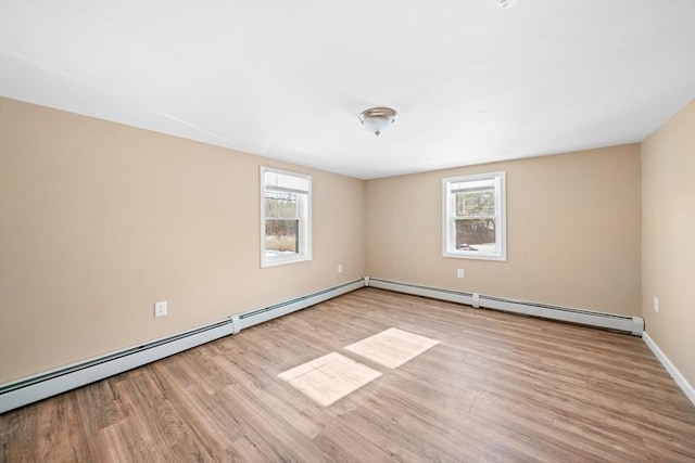 empty room with a healthy amount of sunlight, light wood-style flooring, and baseboard heating