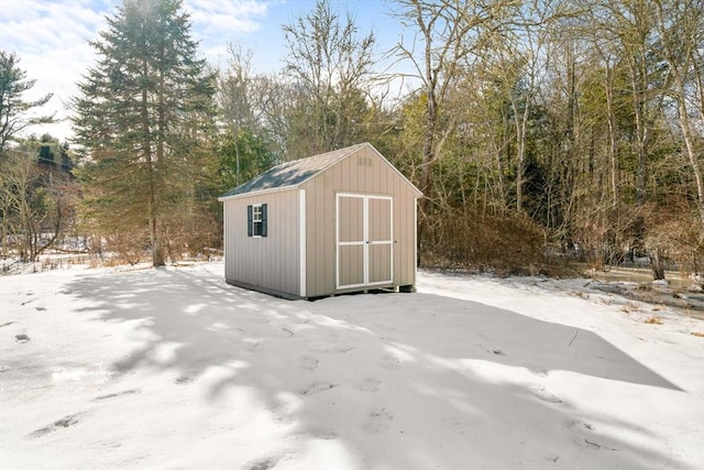 snow covered structure featuring an outbuilding and a shed