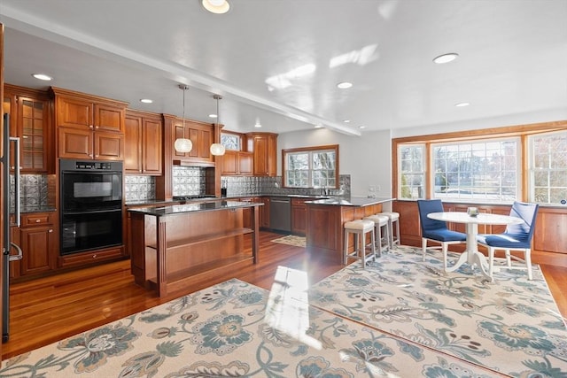 kitchen with a breakfast bar, tasteful backsplash, a center island, stainless steel appliances, and brown cabinetry