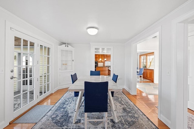 dining room with light wood-style flooring, baseboards, and ornamental molding