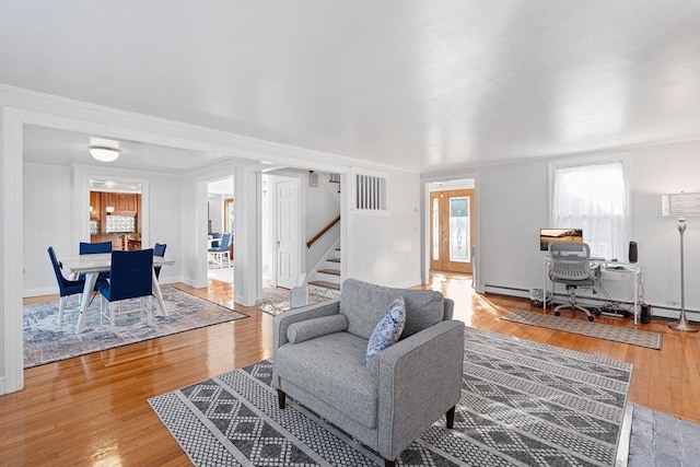 living area with visible vents, wood finished floors, stairway, baseboards, and baseboard heating