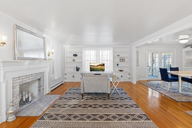 living room with a brick fireplace, wood finished floors, built in shelves, and a baseboard radiator