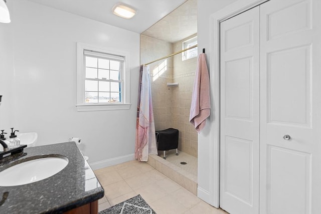 full bath featuring vanity, plenty of natural light, baseboards, and a tile shower