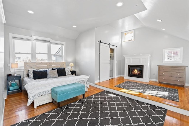 bedroom featuring recessed lighting, wood finished floors, a barn door, and vaulted ceiling