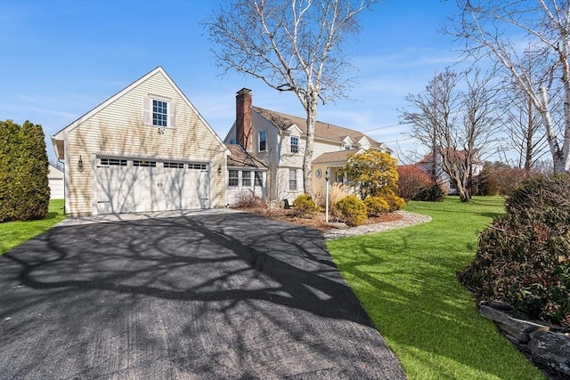 view of front of property with a garage, driveway, a chimney, and a front lawn