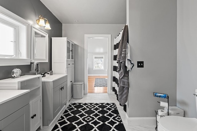 full bath featuring vanity, toilet, baseboards, and marble finish floor