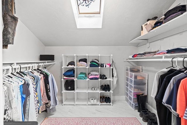 spacious closet with vaulted ceiling with skylight and marble finish floor