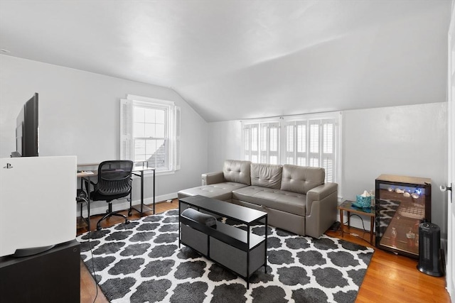 living area with a wealth of natural light, baseboards, wood finished floors, and vaulted ceiling